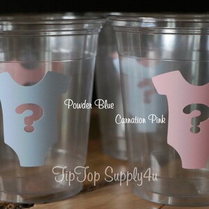 May include: Two clear plastic cups with a question mark inside a baby onesie. The onesie on the left cup is powder blue and the onesie on the right cup is carnation pink. The text "Powder Blue" and "Carnation Pink" is printed below the cups. The text "Tip Top Supply4u" is printed below the cups.