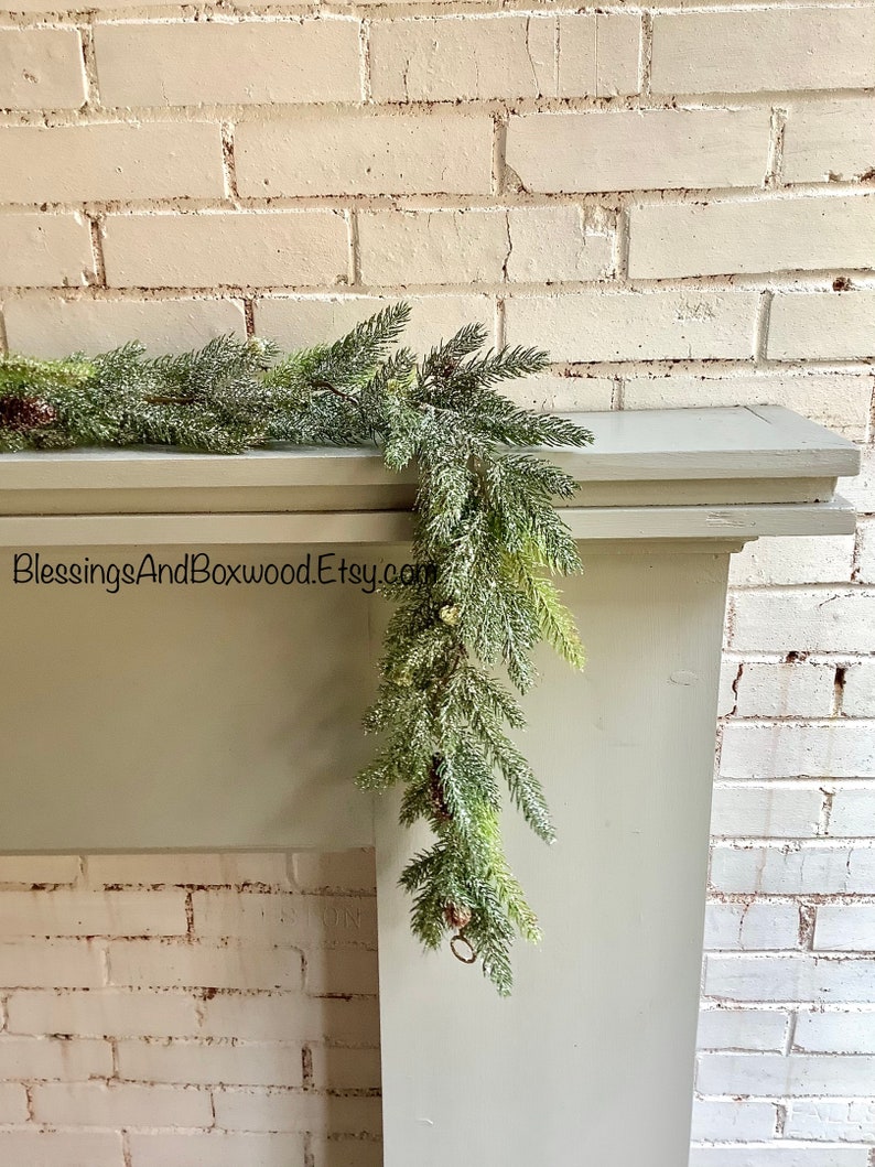Peut inclure: Une guirlande floqu&eacute;e verte avec un mur de briques blanches en arri&egrave;re-plan. La guirlande est drap&eacute; sur une chemin&eacute;e blanche. Le texte "BlessingsAndBoxwoodEtsy.com" est visible sur l'image.
