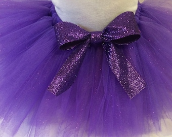 May include: Purple tulle tutu with a sparkly purple bow. The tutu is made of soft, sheer fabric and is perfect for a special occasion.