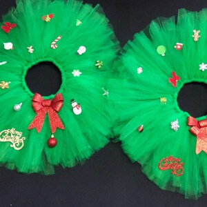 May include: Two green tulle Christmas tree skirts with red bows and various Christmas decorations, including ornaments, snowflakes, candy canes, and a snowman.
