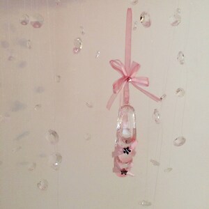 Peut inclure: Une pantoufle en cristal rose avec un n&oelig;ud rose suspendu &agrave; une cha&icirc;ne de cristaux.