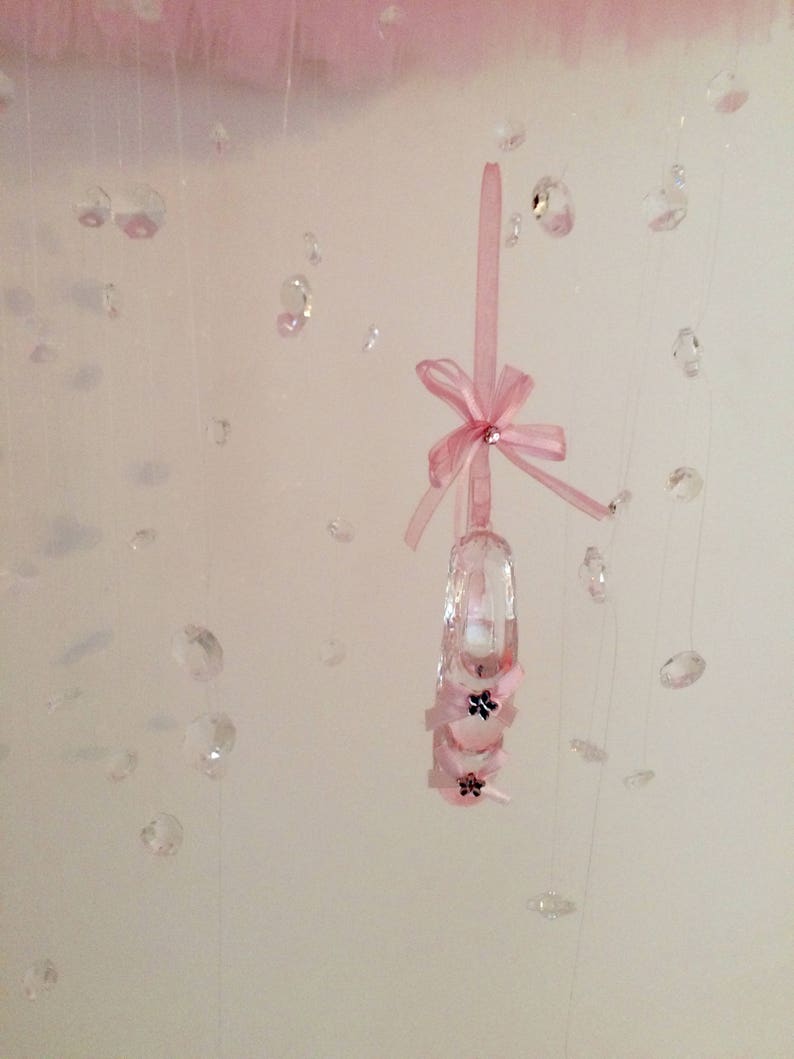 Peut inclure: Une pantoufle en cristal rose avec un n&oelig;ud rose suspendu &agrave; une cha&icirc;ne de cristaux.