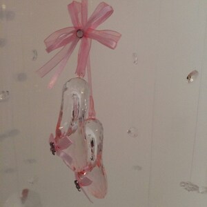 Peut inclure: Une paire de ballerines en cristal rose avec un n&oelig;ud en ruban rose suspendu &agrave; une ficelle.
