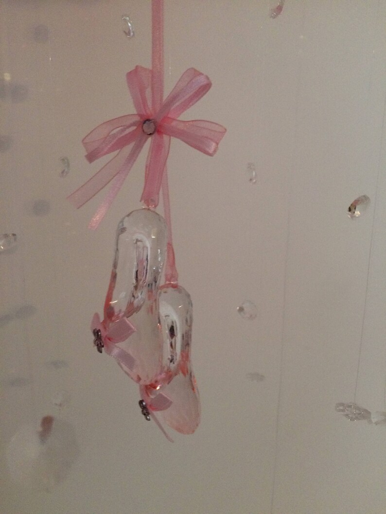 Peut inclure: Une paire de ballerines en cristal rose avec un n&oelig;ud en ruban rose suspendu &agrave; une ficelle.