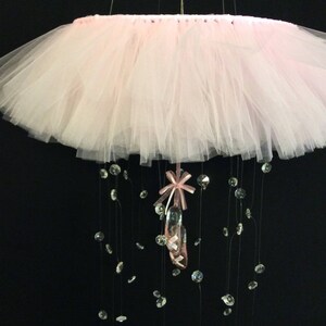 Peut inclure: Un mobile en tulle rose avec un charme de chaussure de ballet rose et des accents de cristal.