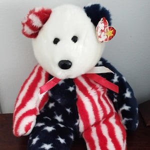 May include: A set of three ceramic mugs with a speckled, cream-coloured glaze. Each mug features a different hand-painted floral design in shades of blue, green, and yellow. The mugs have a simple, modern shape.