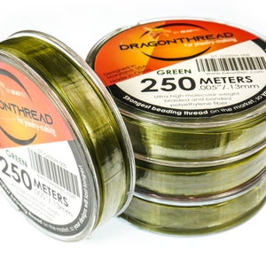 May include: Four spools of green Dragonthread beading thread, each spool containing 250 meters (0.005 inches / 1.13 mm) of ultra-high molecular weight braided and bonded polyethylene fiber. The spools are stacked on top of each other.