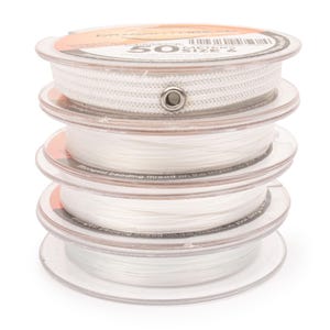 May include: A stack of four clear plastic spools containing white beading thread. The top spool features a white woven band with a single metal eyelet and text that reads DragonThread, 50 meters, and size 6. The other three spools hold thin white thread.