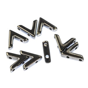 May include: A group of silver metal arrow-shaped beads with two holes each. The beads are arranged in a circle with one bead in the center.