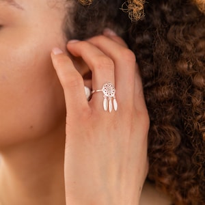 Könnte beinhalten: Ein silberner Ring mit einem zarten Traumfänger-Design und baumelnden Federn.