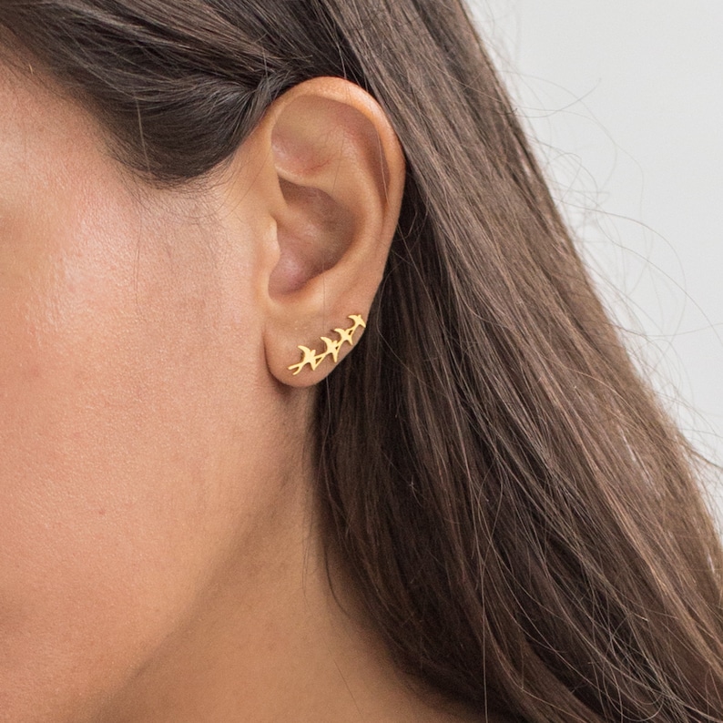 May include: Gold ear cuff with a row of five small bird silhouettes.