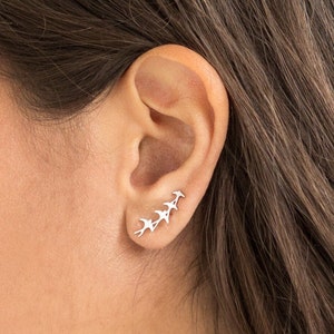 May include: Silver ear cuff featuring a design of five birds flying in a row.