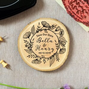 Puede incluir: Un letrero de madera para guardar la fecha con un dise&ntilde;o floral y el texto "Save Our Date Bella & Henry 09-15-2018".
