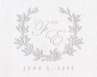 May include: A white embossed paper with a wreath design and the initials "F & E" in a script font. The date "JUNE 3, 2023" is printed below the wreath. A silver self-inking stamp with a black handle is in the lower left corner. The stamp has the word "Shiny" and "MODEL-EM" printed on it.