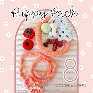 May include: A collection of eight crochet puppy accessories, including a bone, a bow, and two red flower-shaped toys. The set also features a circular toy with a light blue and white design, and a coral-colored rope. The words "Puppy Pack" are at the top.