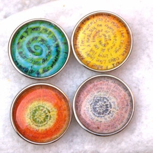 Puede incluir: Cuatro botones redondos, con borde plateado, de vidrio, con diseños coloridos en espiral y texto inspirador. El texto en el botón amarillo dice: "Days like today I feel powerful, less to make a healthy or overuse the thought of the change I must be willing to make the greater", el texto en el botón rosa dice: "Days like today I feel powerful, less to make a healthy or overuse the thought of the change I must be willing to make the greater", el texto en el botón azul dice: "Days like today I feel powerful, less to make a healthy or overuse the thought of the change I must be willing to make the greater", y el texto en el botón naranja dice: "Days like today I feel powerful, less to make a healthy or overuse the thought of the change I must be willing to make the greater".