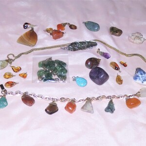 May include: A collection of gemstone pendants and charms, including amethyst, agate, amber, turquoise, and jade. The stones are various shapes and sizes, and some are strung on a gold chain.