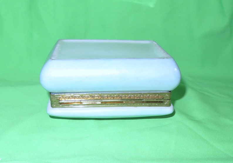 May include: A light blue ceramic trinket box with a gold trim and a hinged lid.