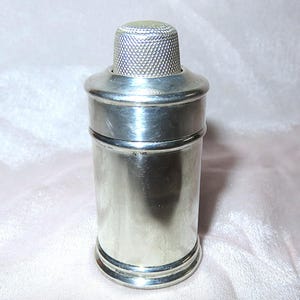 Op de afbeelding: Een zilveren thimble met een decoratieve bovenkant, gebruikt als flessenstop.