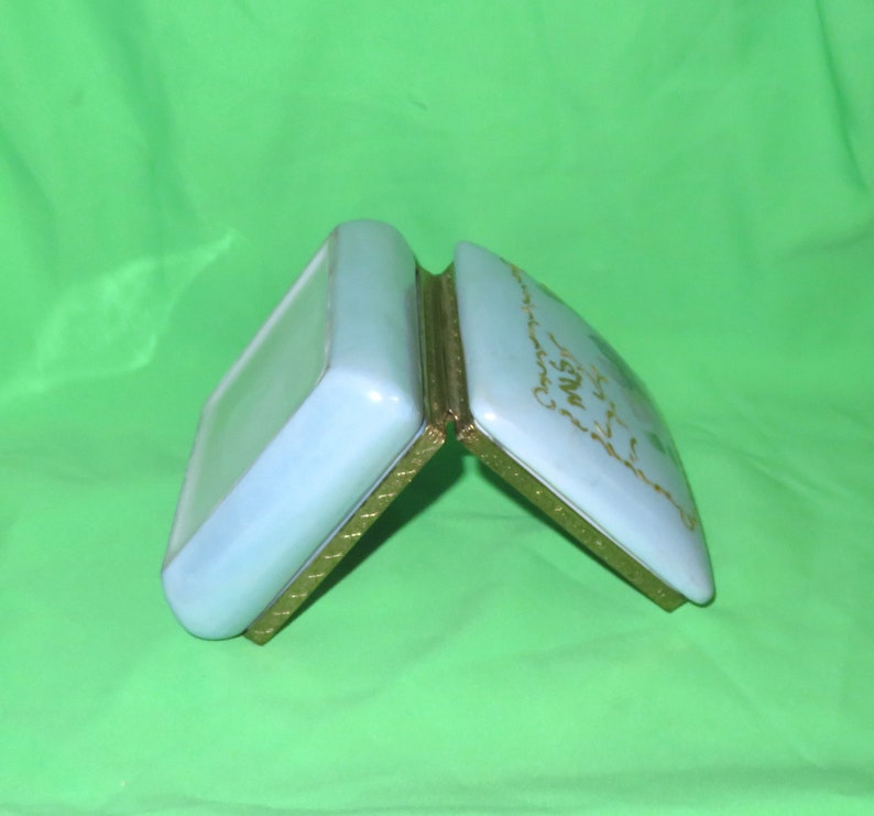 May include: A light blue porcelain trinket box with gold trim and a gold inscription that reads "Our First Christmas Together".