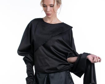 May include: A black, asymmetrical dress with a long skirt and a draped top. The dress is made of a soft, flowing fabric.