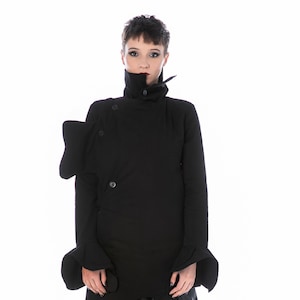 以下が含まれることがあります： 非対称デザインの黒いアバンギャルドコート。ハイカラー、ボタン留め、肩と袖にユニークな彫刻的ディテールが特徴です。長い黒いスカートと黒いコンバットブーツが含まれています。