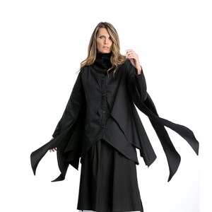May include: A black long-sleeved shirt with a high collar and a long skirt. The shirt has a layered design and the skirt has a white underskirt.