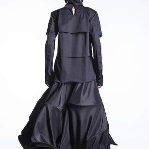 May include: A black long-sleeved shirt with a layered design and a black skirt with a flowing, ruffled hem.