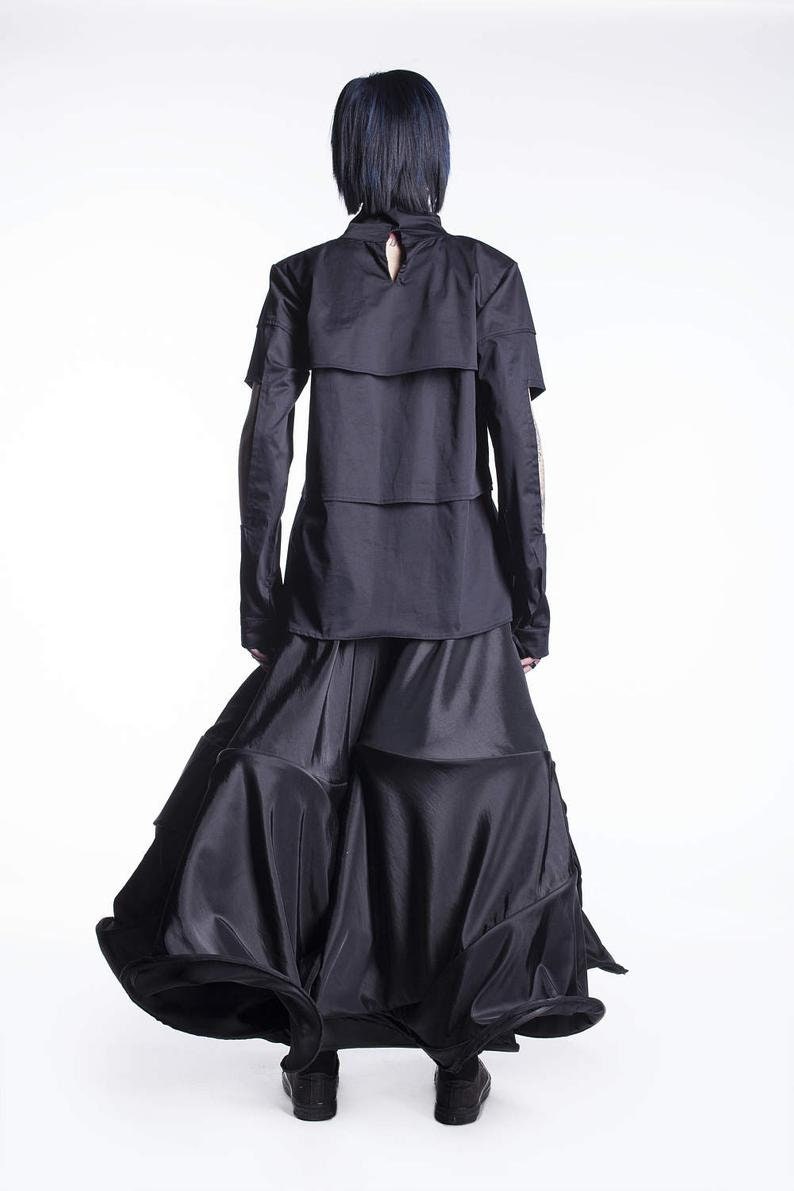 May include: A black long-sleeved shirt with a layered design and a black skirt with a flowing, ruffled hem.
