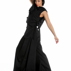 May include: A woman wearing a black sleeveless top and wide-legged trousers. The top has a tie at the back and the trousers have a wide, flowing silhouette.
