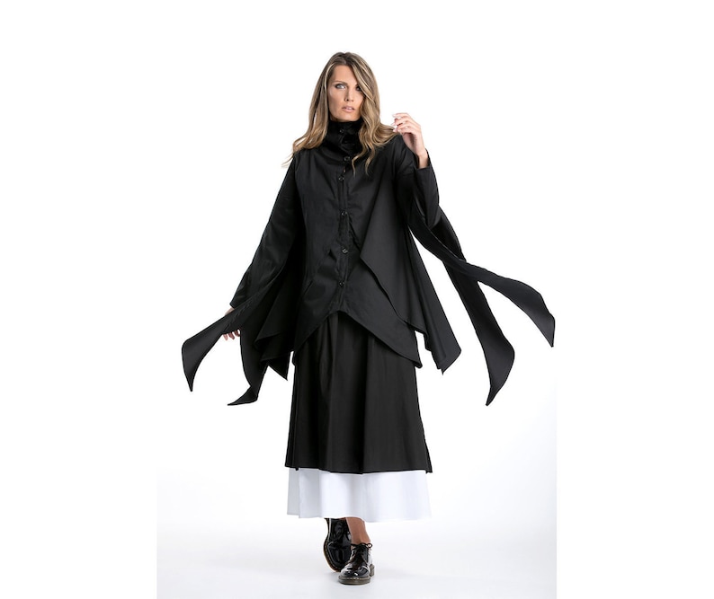 May include: A black long-sleeved shirt with a high collar and a long skirt. The shirt has a layered design and the skirt has a white underskirt.