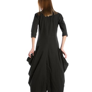K&ouml;nnte beinhalten: Ein schwarzes, lang&auml;rmeliges Kleid mit einem flie&szlig;enden Rock und einem Schlitz im R&uuml;cken. Das Kleid wird von einer Person mit langen braunen Haaren getragen.