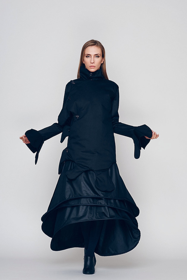 May include: A black long-sleeved dress with a high neck and a layered skirt. The dress has a unique design with a cinched waist and a flowing skirt.