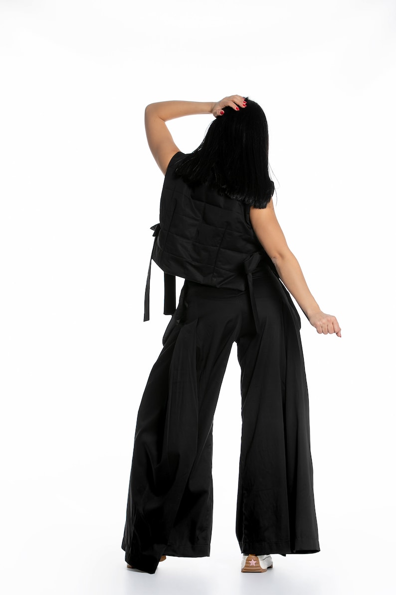 May include: A black sleeveless vest with a quilted design and a matching pair of wide-leg trousers. The vest has a tie at the back and the trousers have a wide waistband.