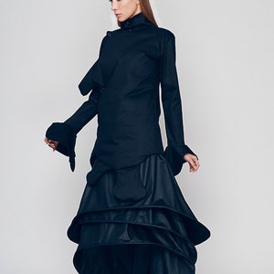 May include: A black long-sleeved shirt with a high collar and a layered skirt. The shirt has a unique design with a folded over collar and a long, flowing skirt.