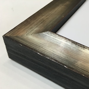 May include: Close-up of a silver and black picture frame with a beveled edge. The frame has a distressed finish and a subtle wood grain pattern.