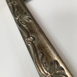 May include: A silver picture frame with ornate detailing. The frame has a distressed finish and a raised design.