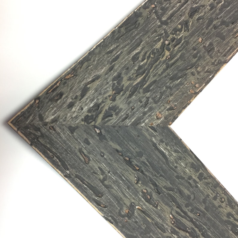 May include: Close-up of a corner of a dark grey wood picture frame with a distressed finish.