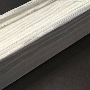 May include: A close-up of a white wooden box with a slightly distressed finish. The box is made of wood planks and has a smooth, even surface.