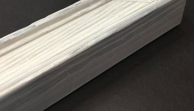 May include: A close-up of a white wooden box with a slightly distressed finish. The box is made of wood planks and has a smooth, even surface.