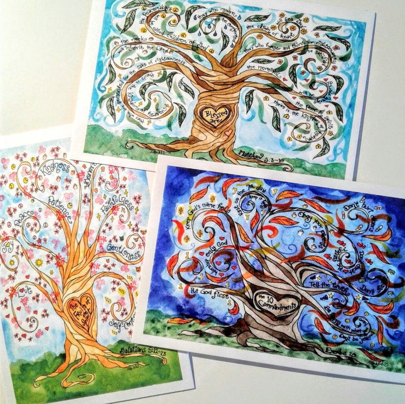 May include: Three watercolor paintings of trees with words and phrases written on the leaves. The first tree has the words "Blessed are" in the center of the trunk and the words "the meek, the poor in spirit, those who mourn, those who hunger and thirst for righteousness, the merciful, the pure in heart, the peacemakers, those who are persecuted for righteousness sake" on the branches. The second tree has the words "Love, Joy, Peace, Patience, Kindness, Goodness, Faithfulness, Gentleness, Self-Control" on the branches. The third tree has the words "Keep God's name holy, The day is the Lord's, Don't hurt or kill, Don't commit adultery, Don't steal, Tell the truth, Don't lie, Don't covet" on the branches. The words "The 10 Commandments" are in the center of the trunk.