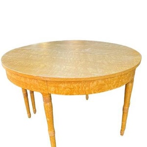 May include: A round wooden table with a light wood finish and four legs. The table top has a unique grain pattern.