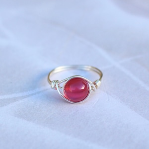 May include: A silver wire ring with a red gemstone.