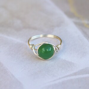 May include: A silver wire wrapped ring with a green gemstone.