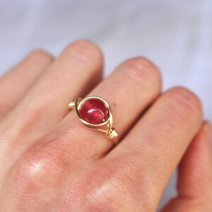 May include: A gold wire wrapped ring with a red gemstone.