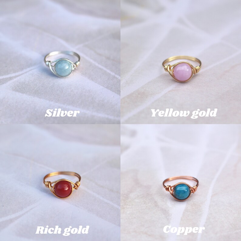 May include: Four wire-wrapped rings with different colored stones and metal finishes. The rings are on a white background. The metal finishes are silver, yellow gold, rich gold, and copper. The stones are light blue, pink, red, and turquoise.