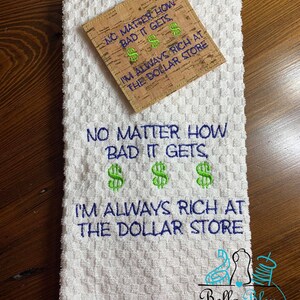 May include: White kitchen towel with green and blue embroidery that reads "No matter how bad it gets, I'm always rich at the dollar store".