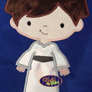May include: Embroidered applique of a cartoon character with brown hair, wearing a white dress with a gray trim and a black belt. The character has a smiling face with black eyes and a pink complexion. The applique is on a blue background with the text "Bella Bleu" in a yellow oval.