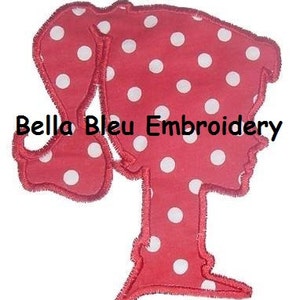 May include: Red fabric applique with white polka dots in the shape of a girl with a ponytail. The applique has the text "Bella Bleu Embroidery" on it.