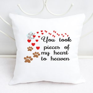 Puede incluir: Almohada blanca con el texto "You took pieces of my heart to heaven" bordado en negro. El texto está rodeado de corazones rojos y huellas de patas marrones.